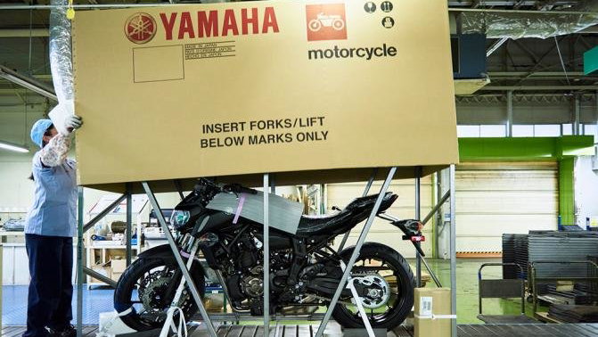 Yamaha motorcycle being placed in packaging for shipping.