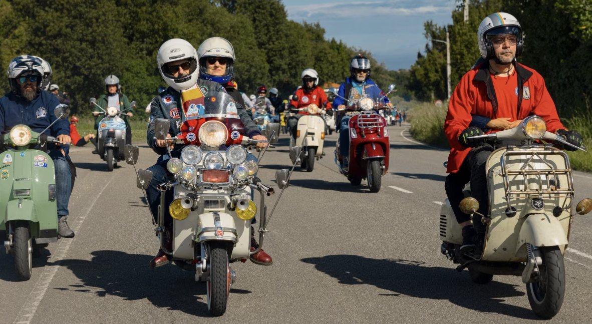 Vespa scooters on the road at World Days event. Credit - Vespa