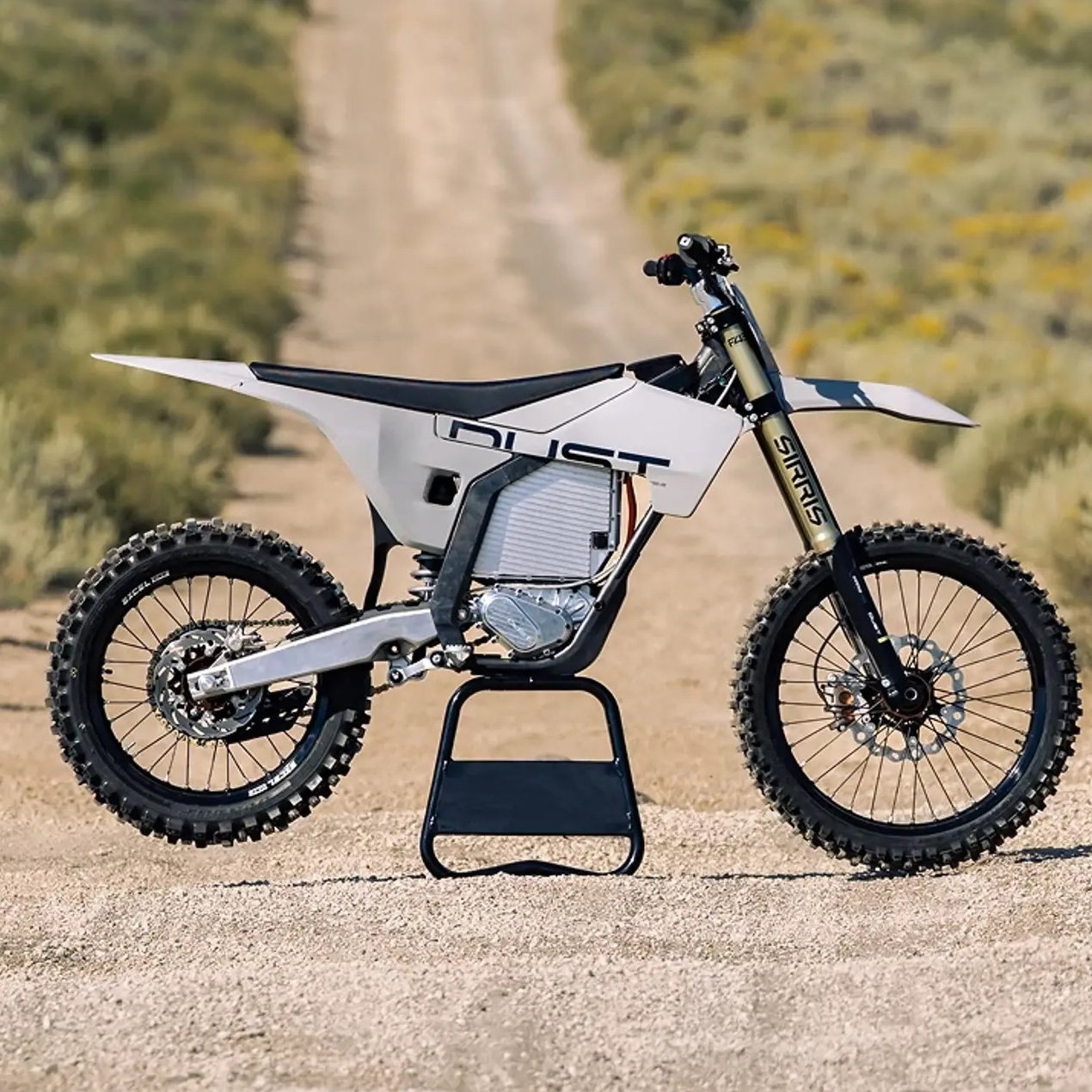 A Dust Moto electric dirt bike on a dusty track