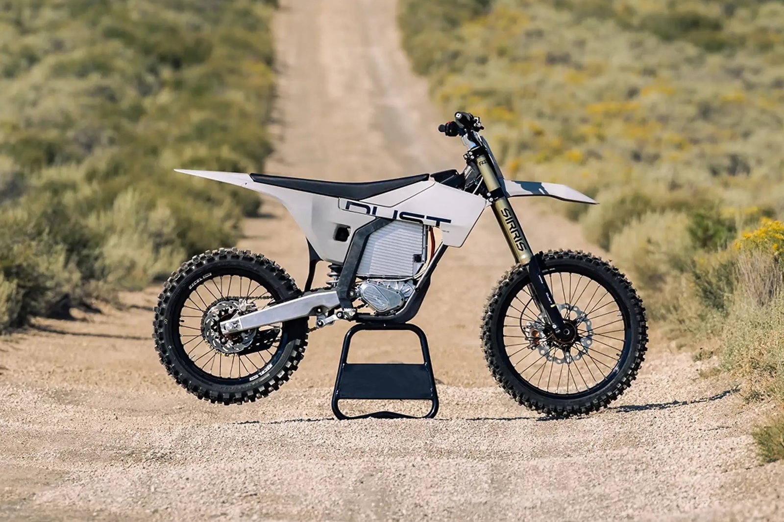 A Dust Moto electric dirt bike on a dusty track