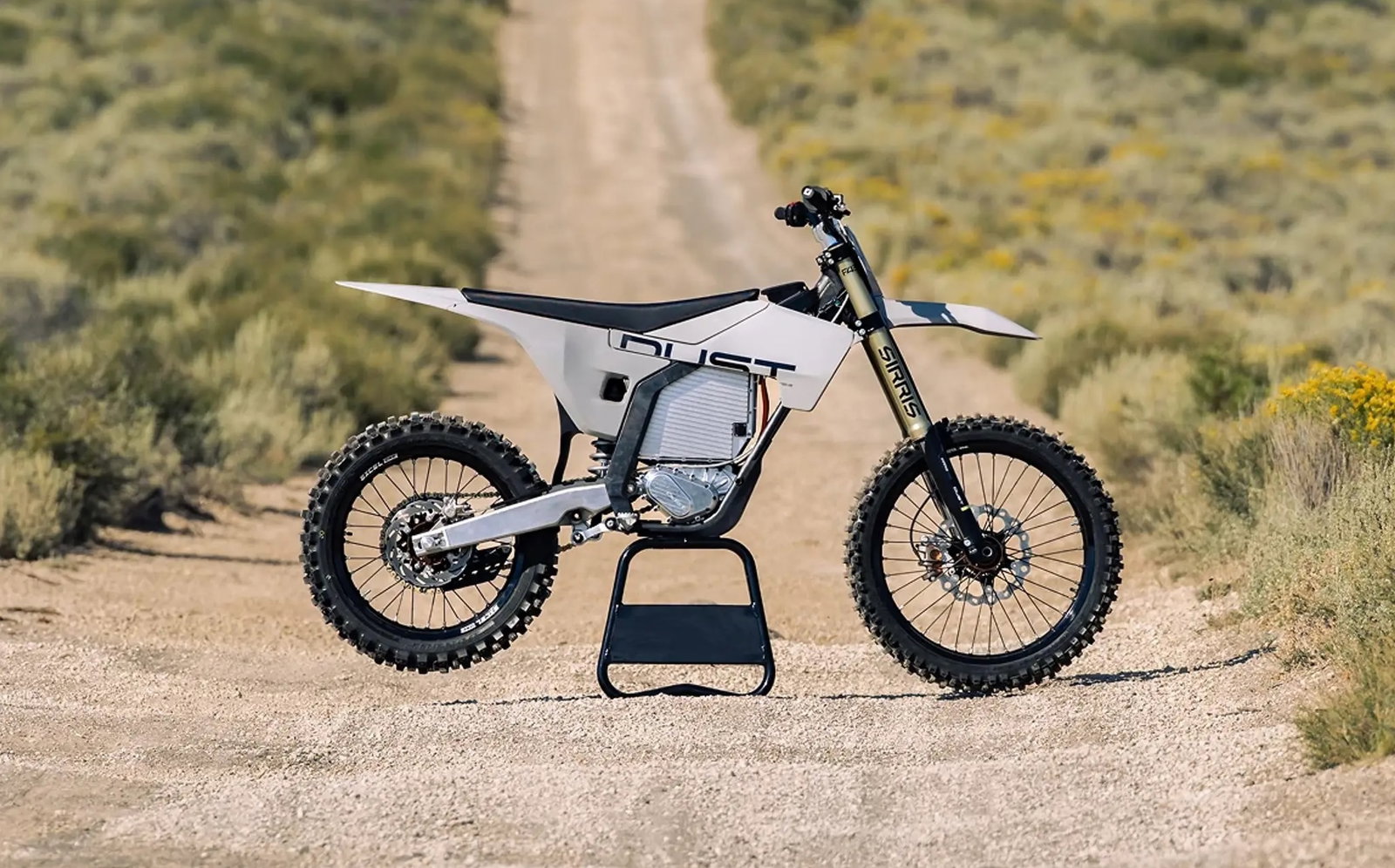 A Dust Moto electric dirt bike on a dusty track