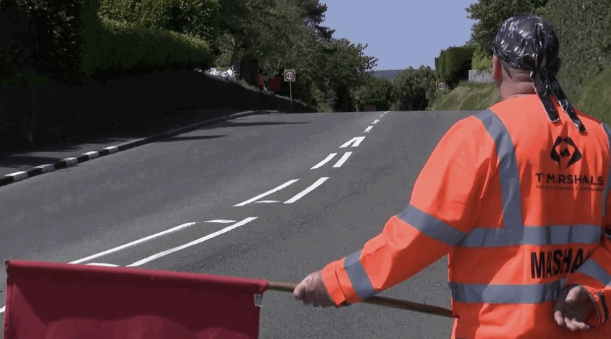 A marshal waving a red flag at the TT. Credit: Isle of Man TT.