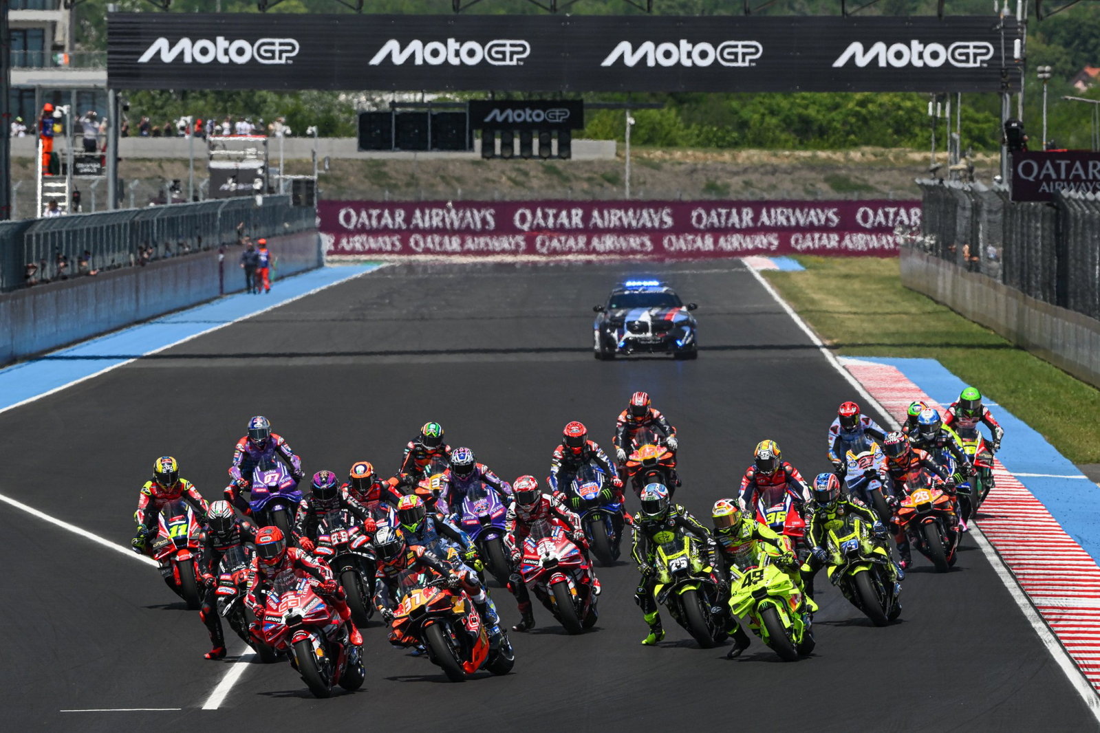 A grid of MotoGP bikes heading into a turn