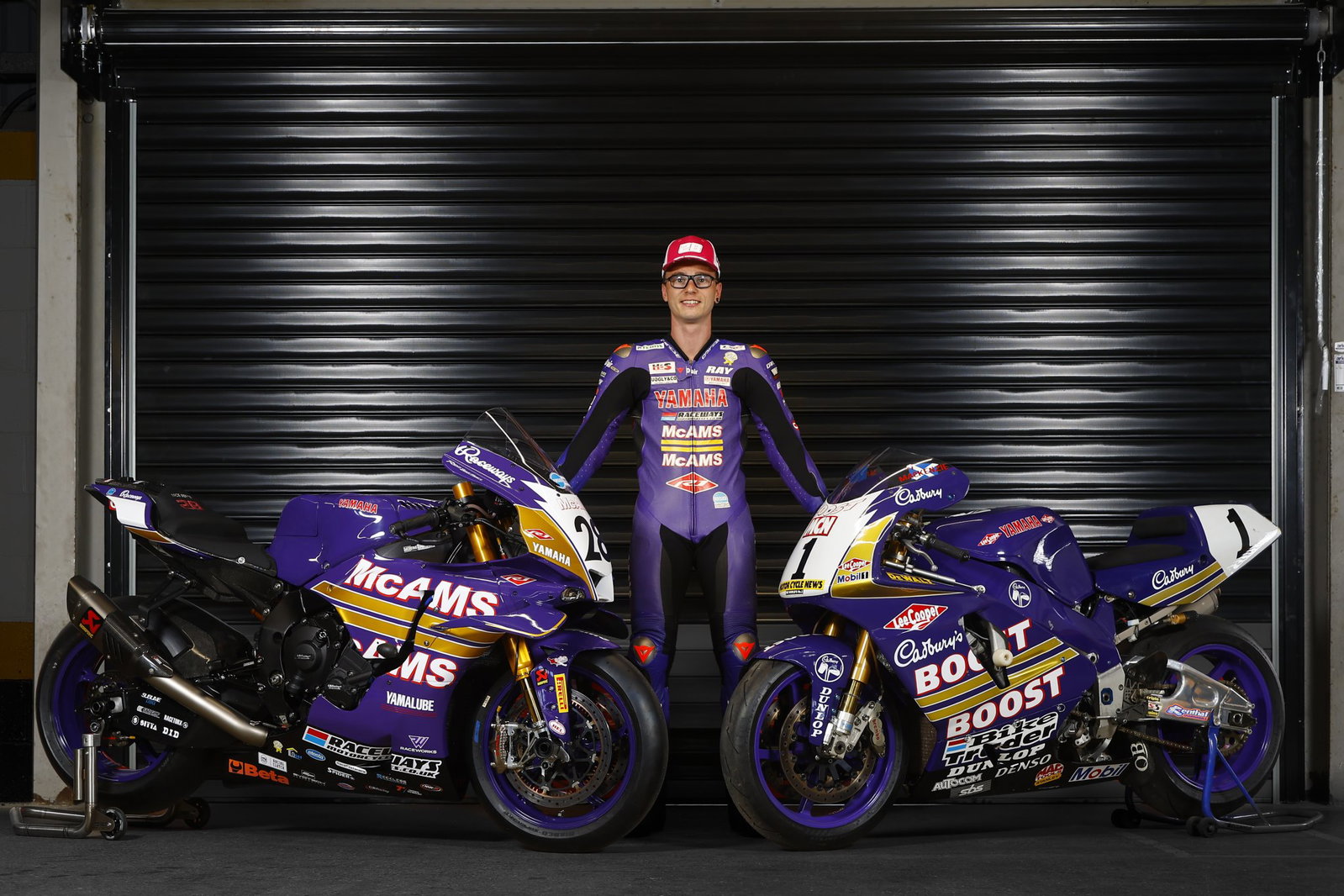 Bradley Ray standing with his McAMS Yamaha and the original Cadbury Boost bike.