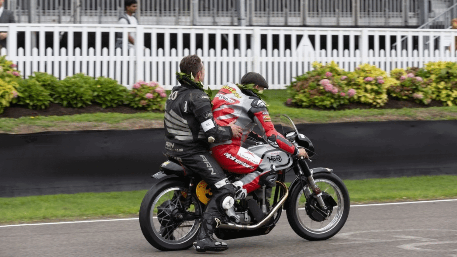 John McGuinness riding a Norton with a passenger.