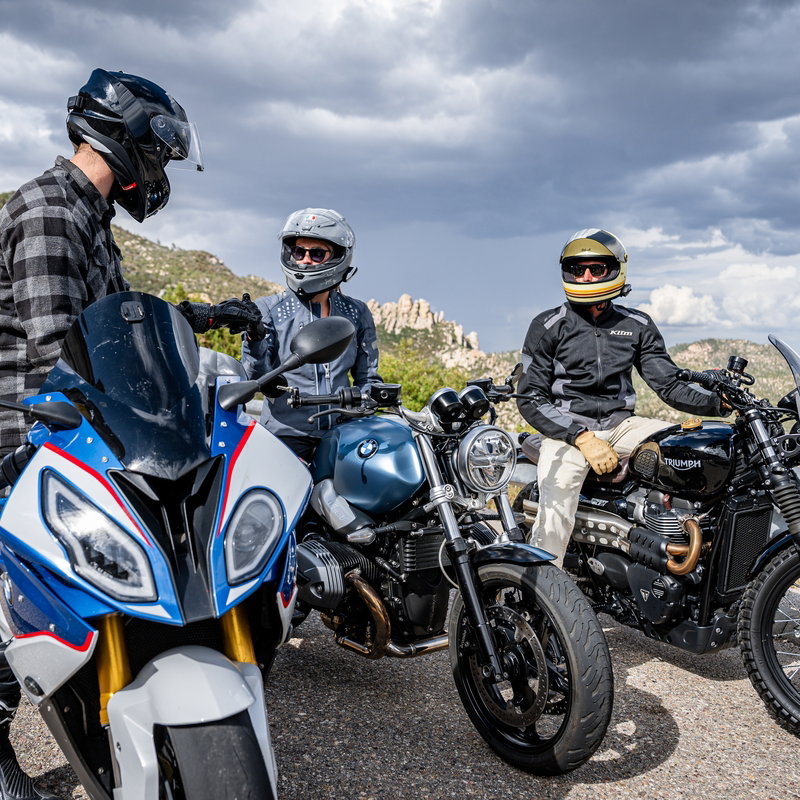 Motorcyclists parked at the side of a road.