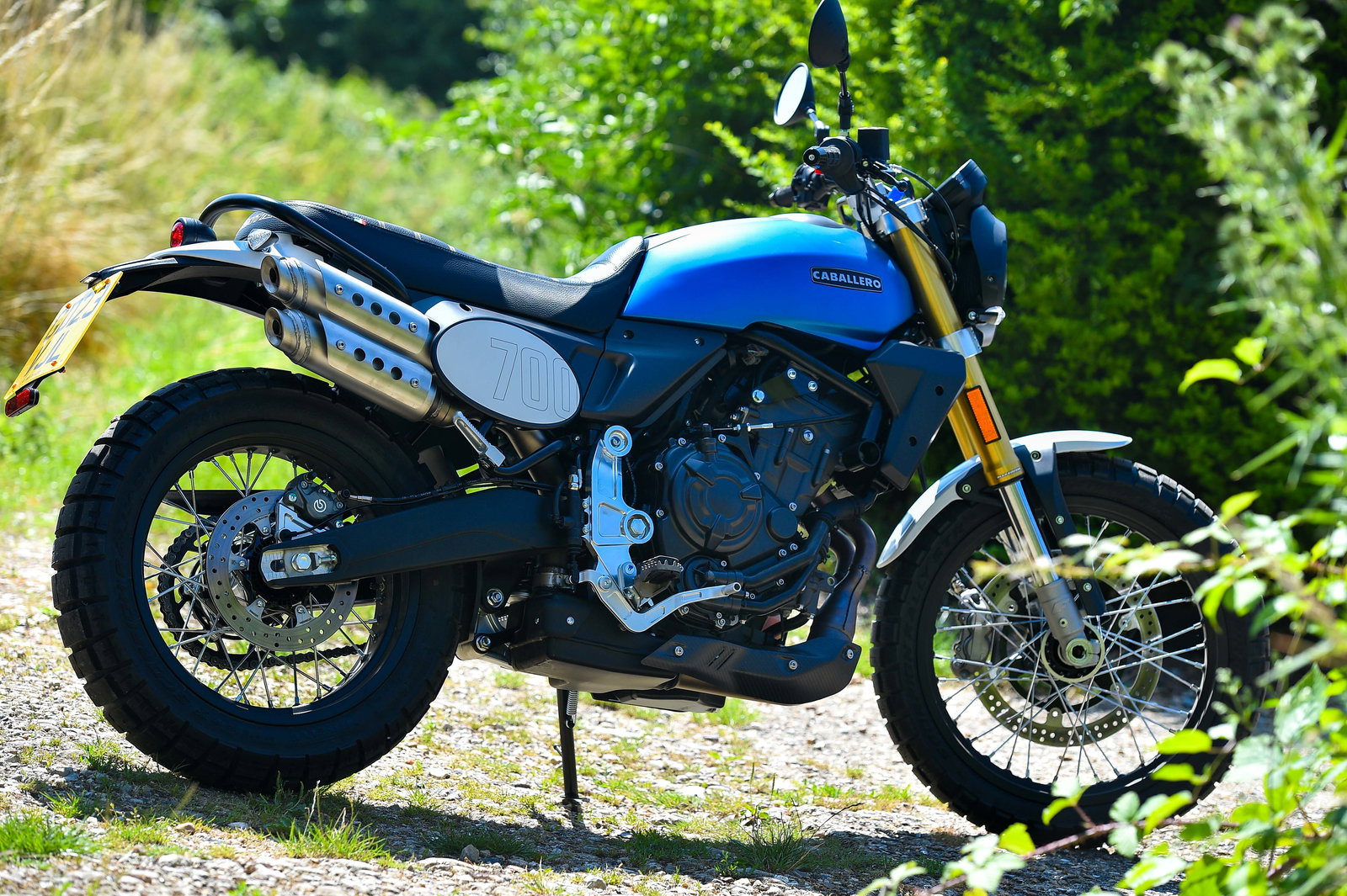 A Fantic motorcycle parked in front of foliage 