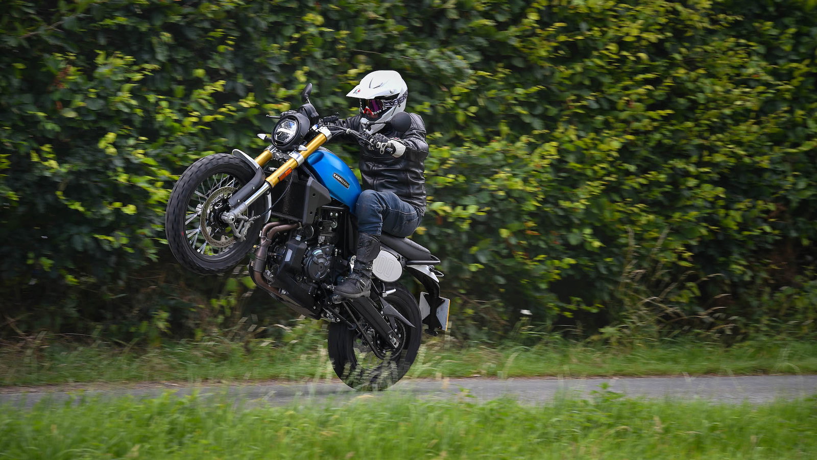 A motorcycle pulls a wheelie on a private road