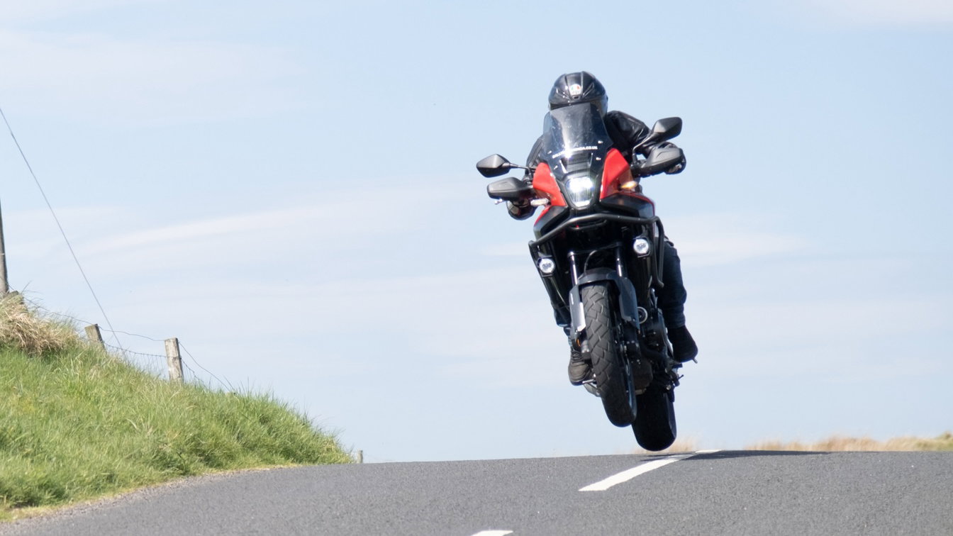A motorcycle cresting a rise in the road