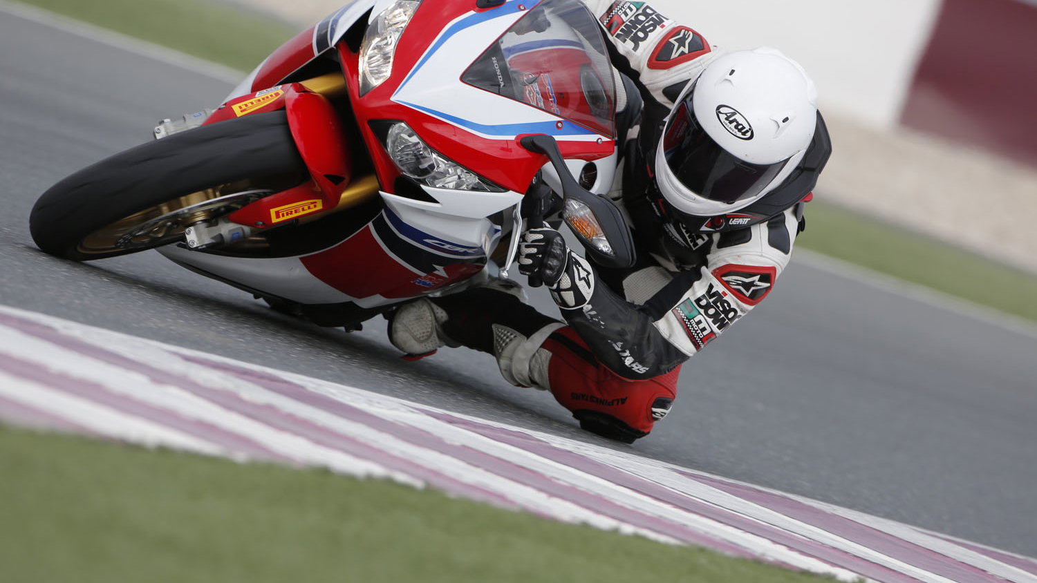 A red, white and blue 2014 Fireblade CBR1000RR-SP being ridden around a racetrack