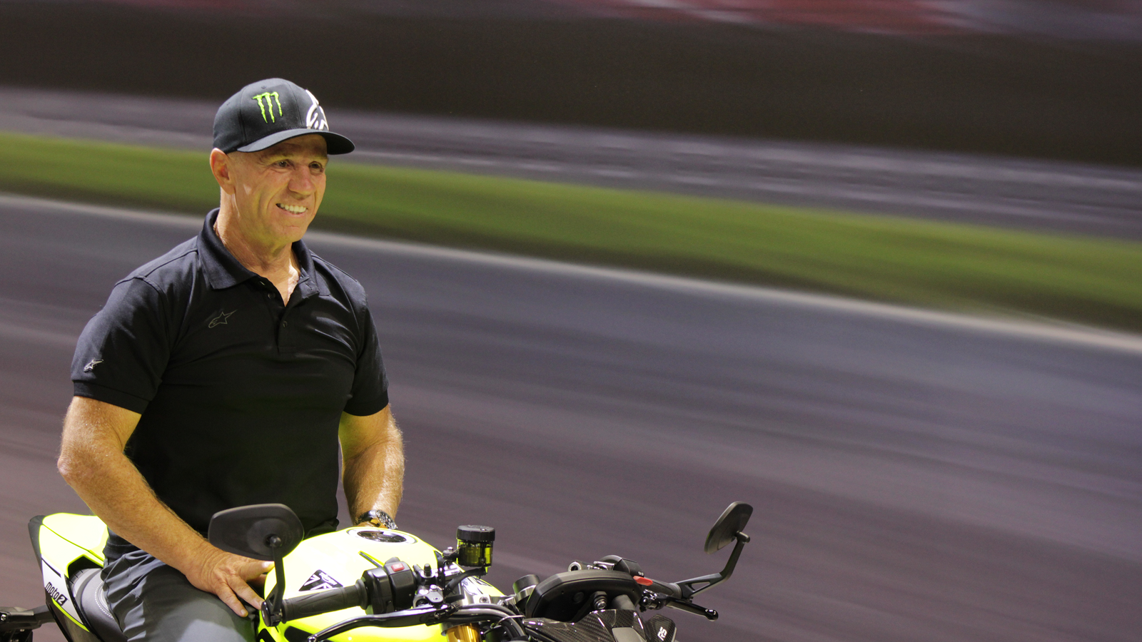 Randy Mamola sitting on Triumph Street Triple 765 Moto2 Edition at Motorcycle Live 2022.